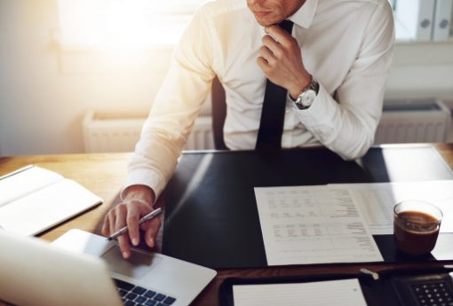 a main working at his desk, laptop, papers,