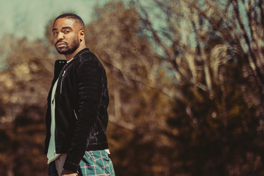 A man in black leather jacket standing outside