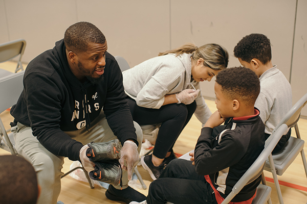 Jonathan Stewart gives shoes to kids. 