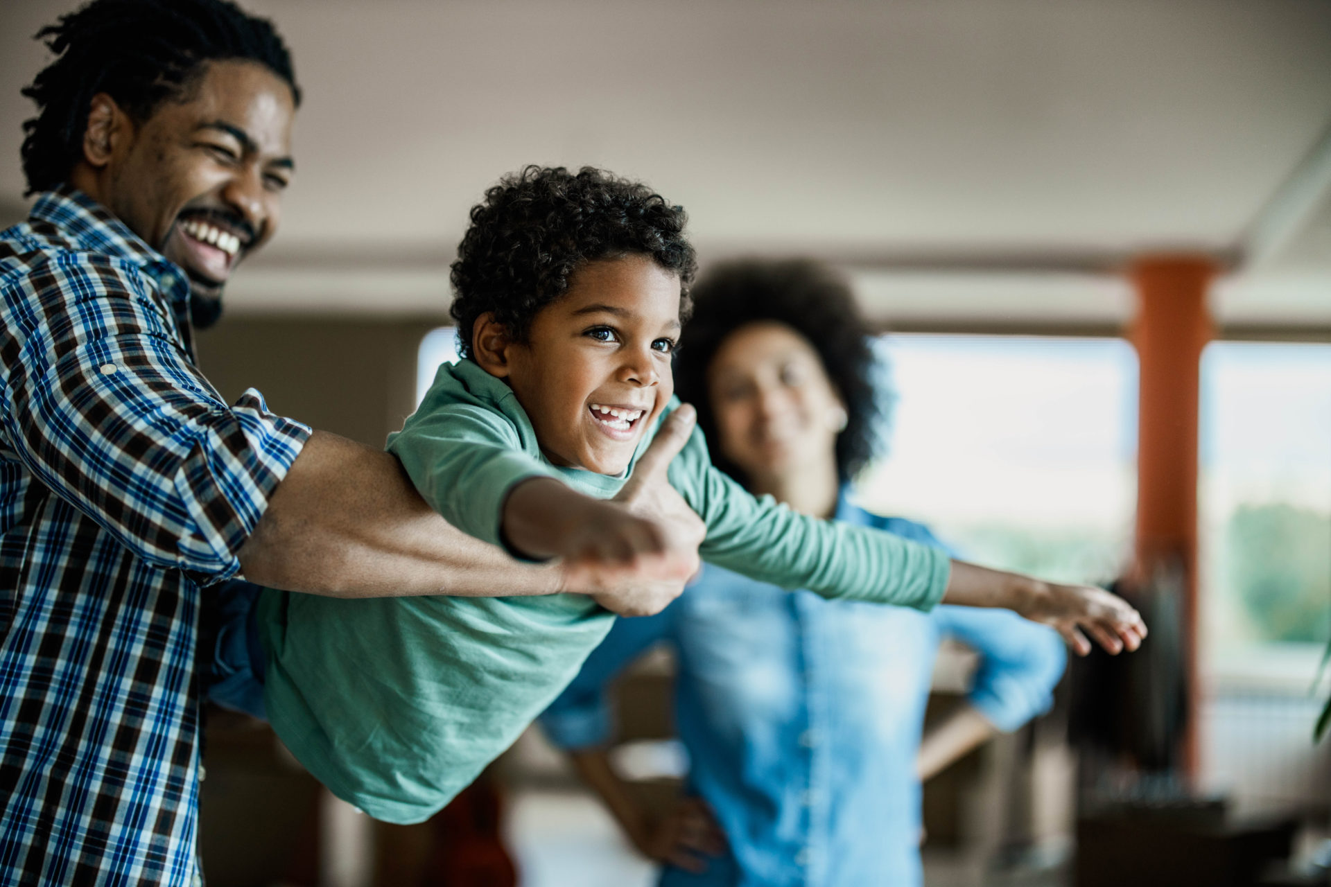 Happy African American boy having fun with his father at home.