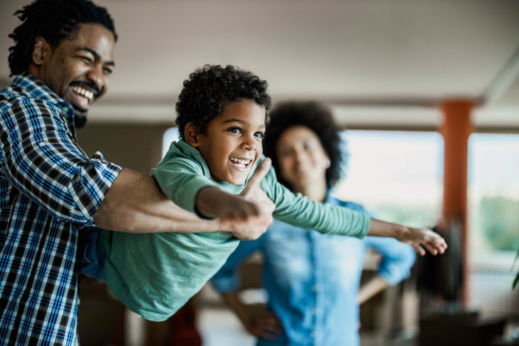 Happy African American boy having fun with his father at home.