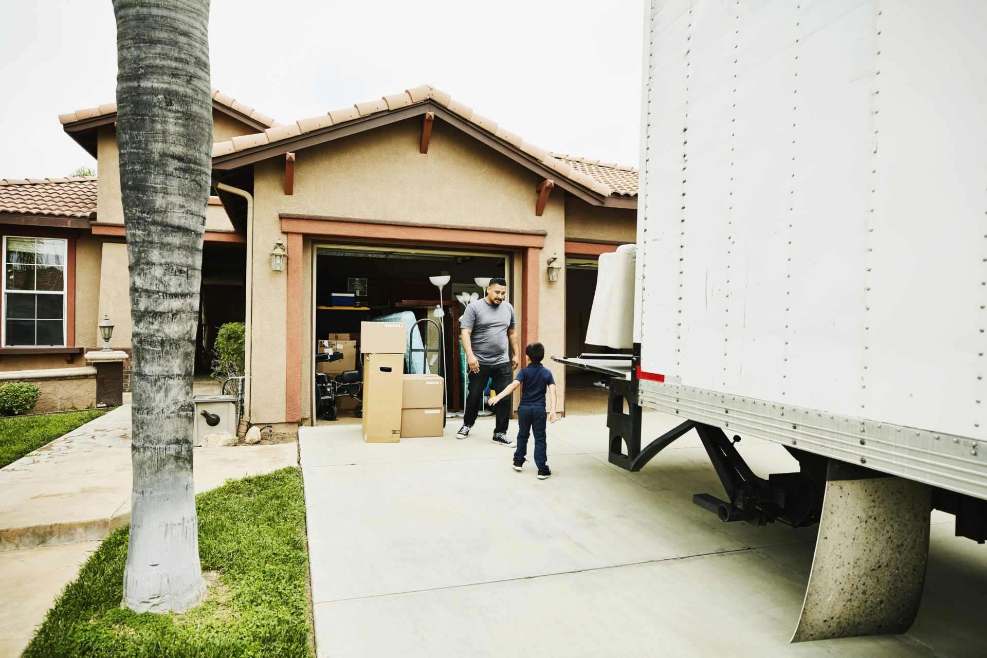 Young son helping father move items from moving truck into new house