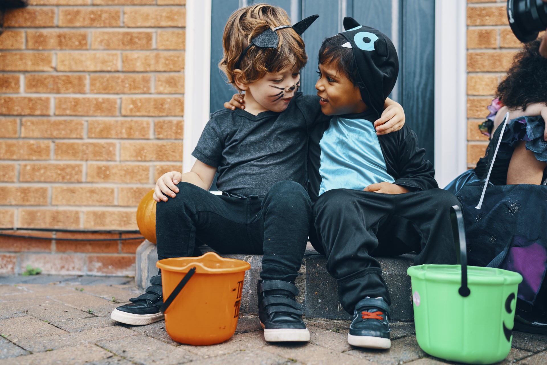 Two children dressed for Halloween with their arms around each others shoulders.