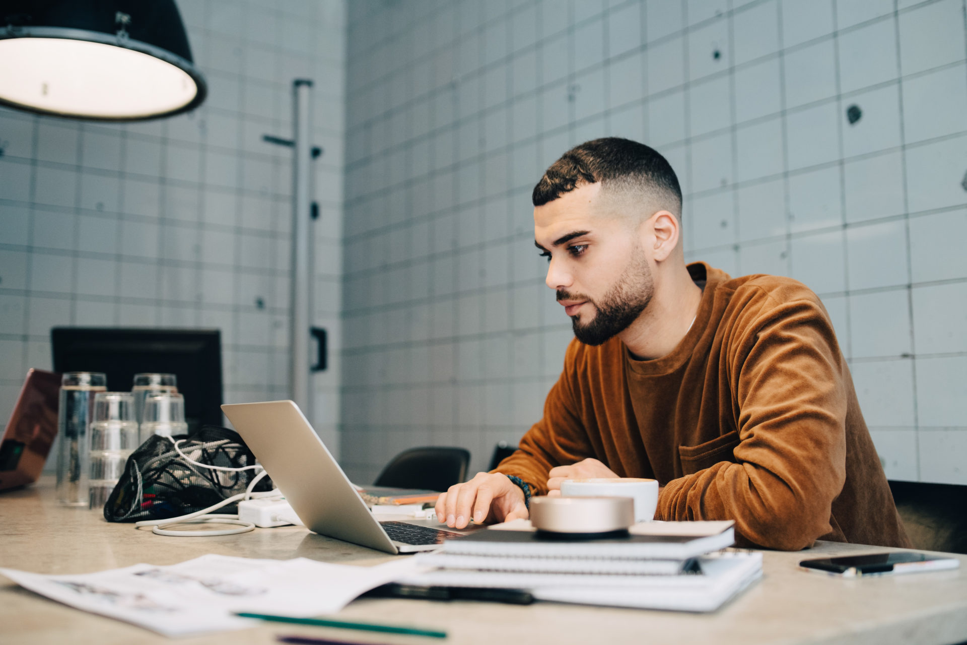 Confident young male computer programmer using laptop at desk in small office