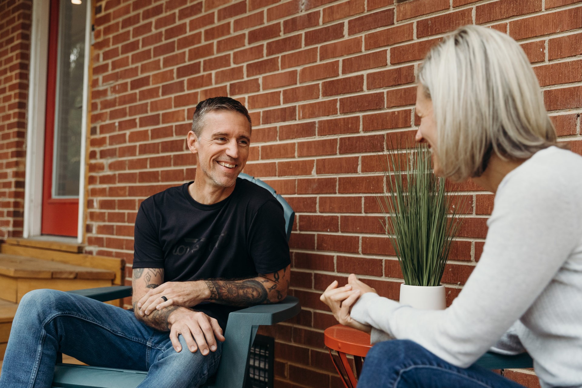 A couple sitting outside their brick house talking