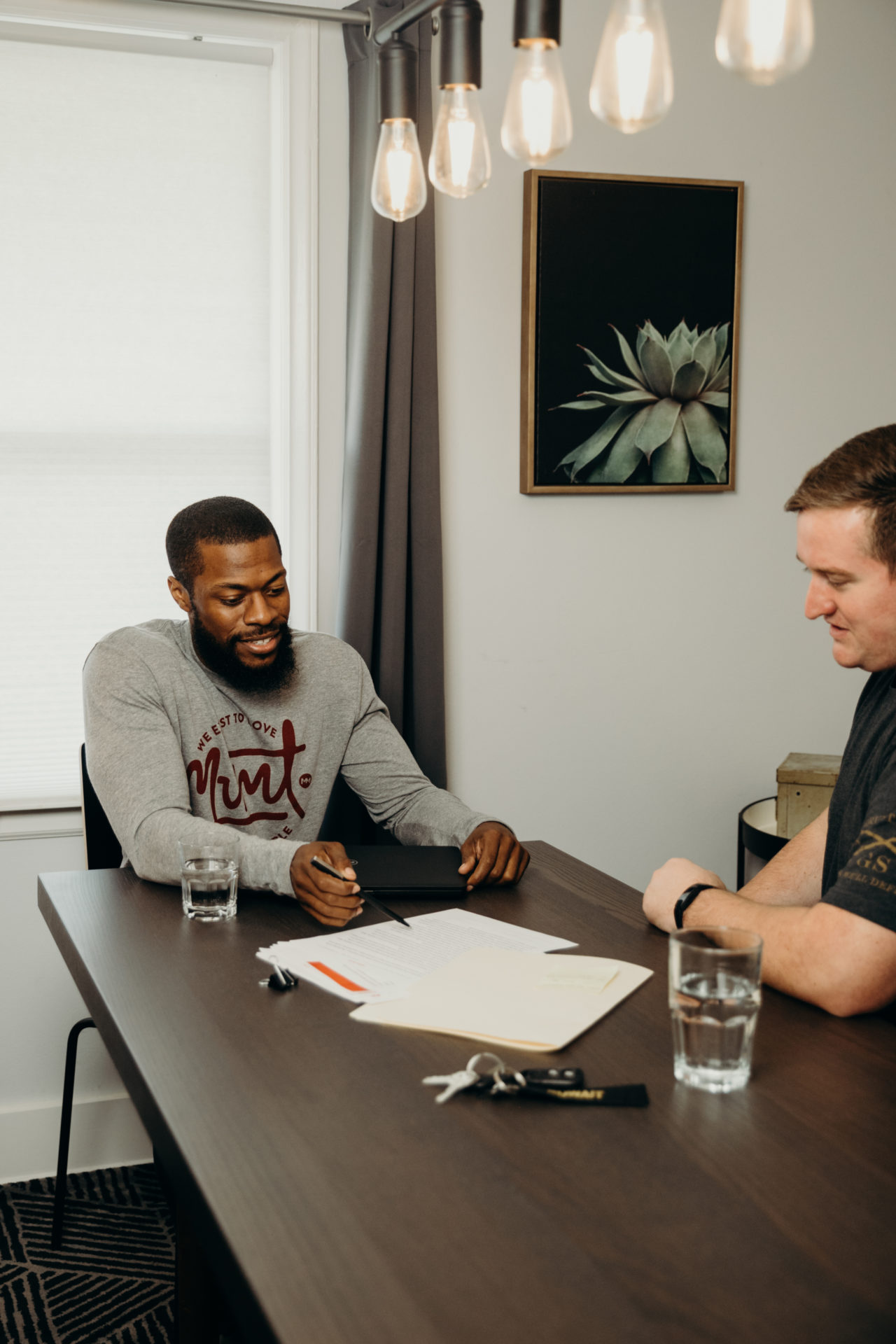 Two man sitting at kitchen table looking over papers