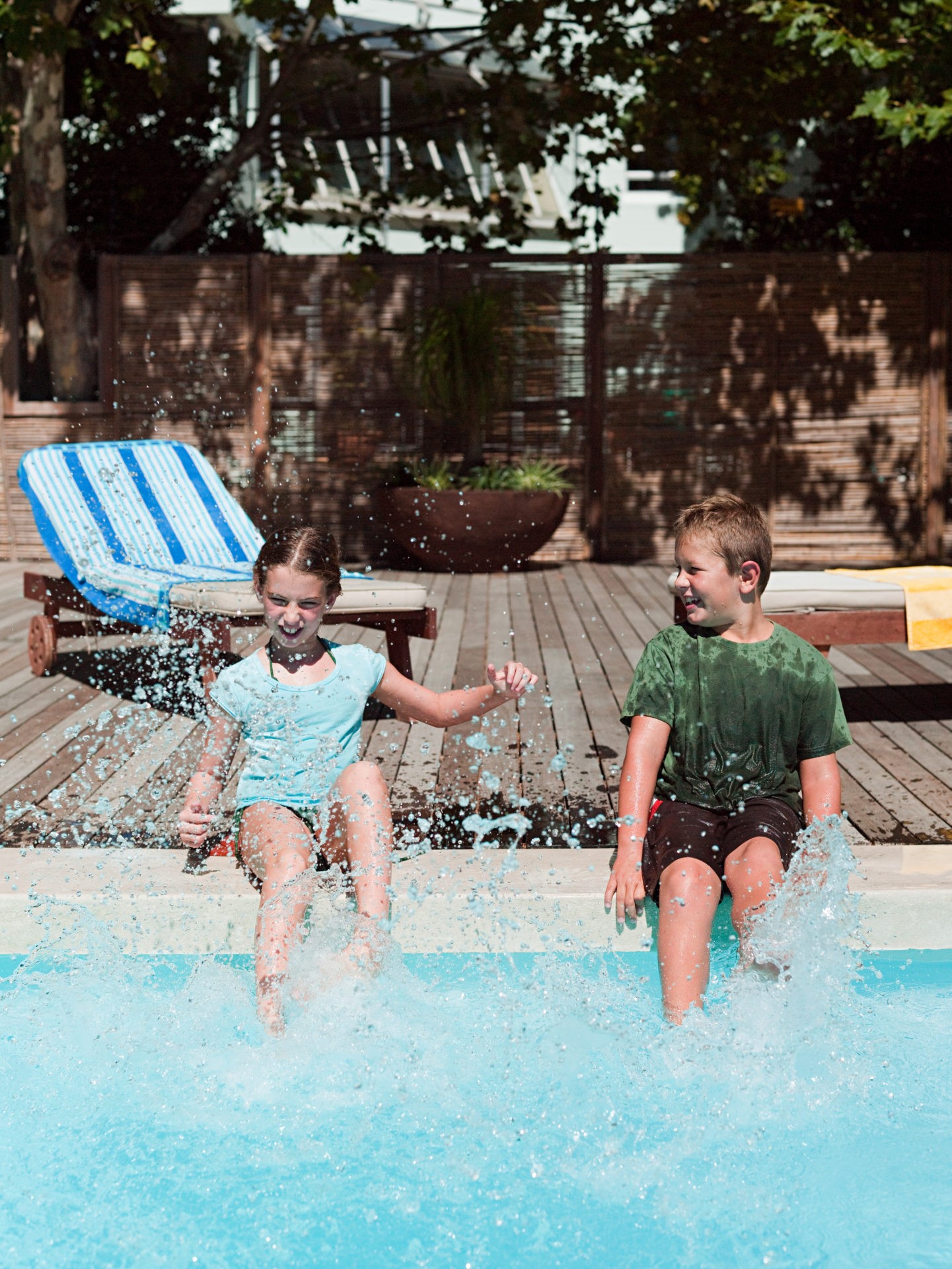 Boy and girl splashing in swimming pool