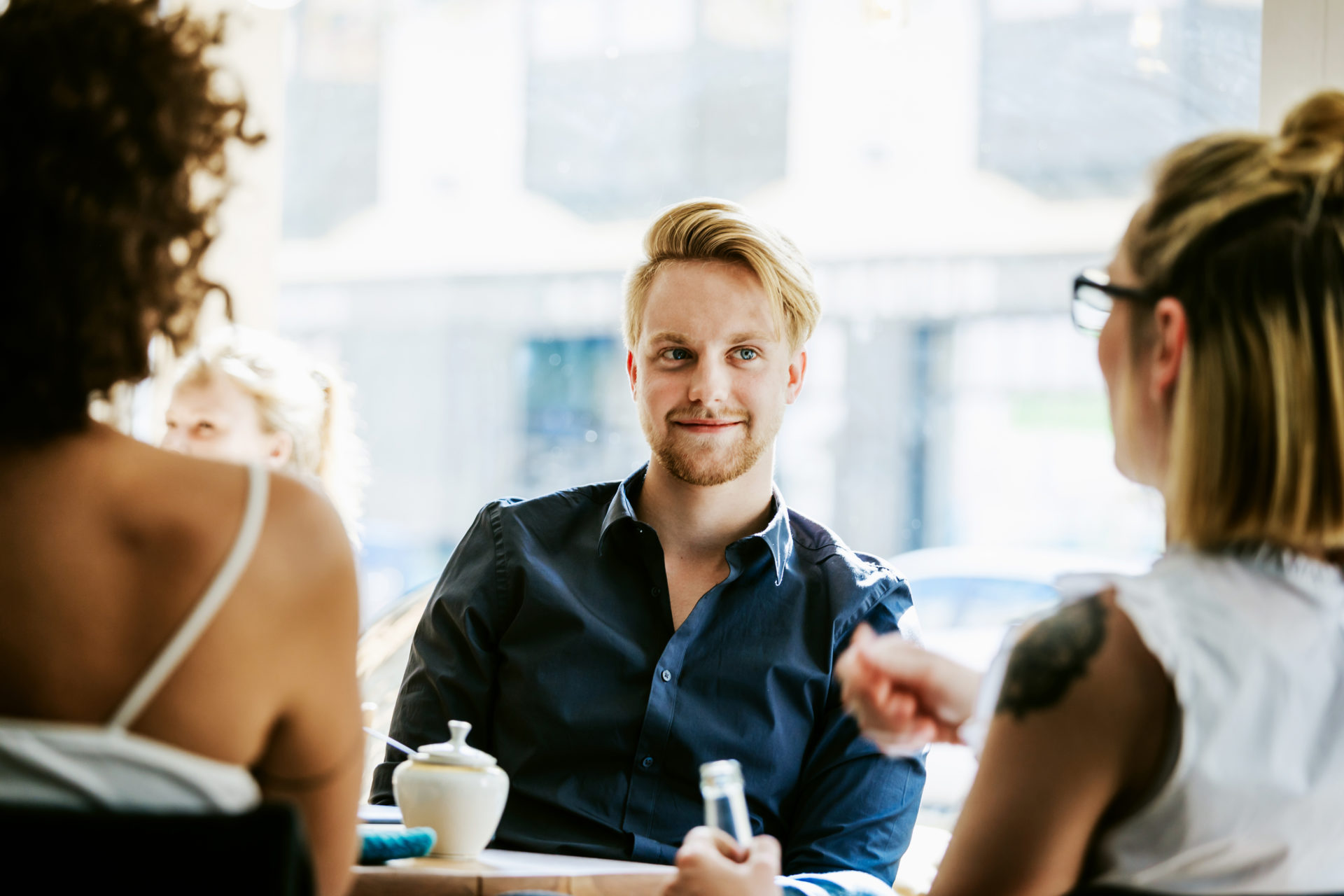 Man Smiling As He Talks With Friends In Cafe