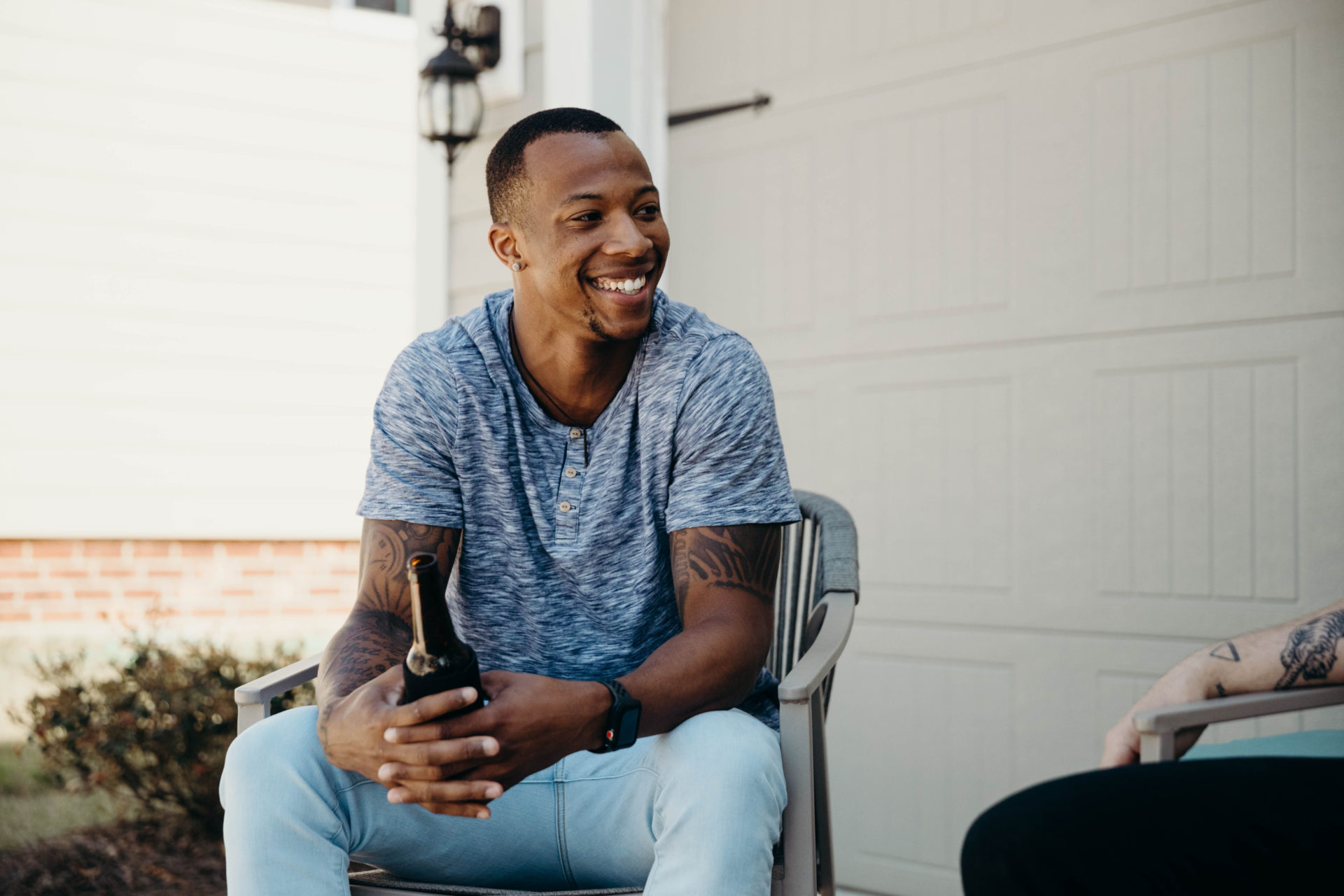 Black male in blue shirt and jeans sitting outside