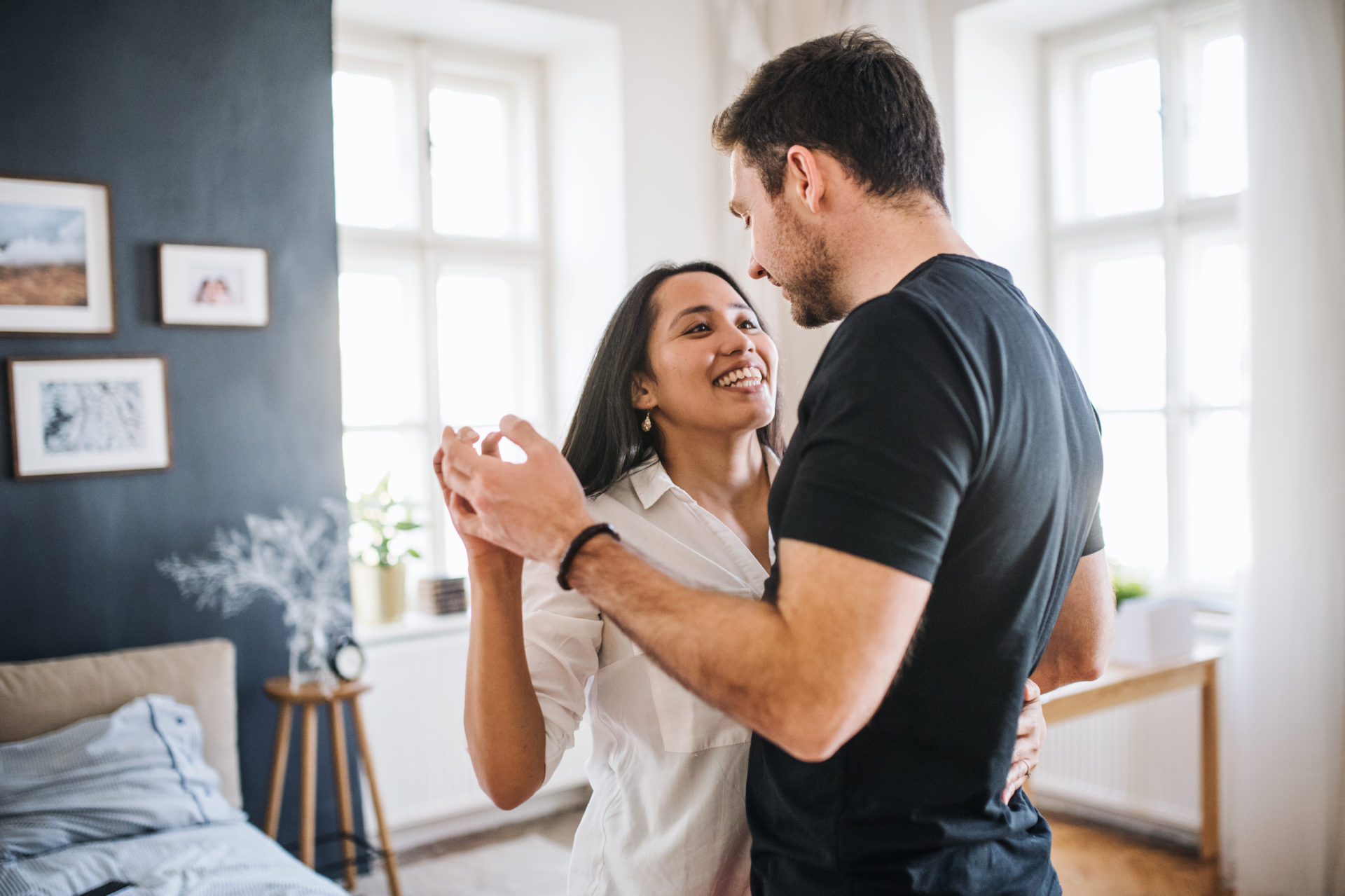 Affectionate young couple in love dancing at home, having fun.