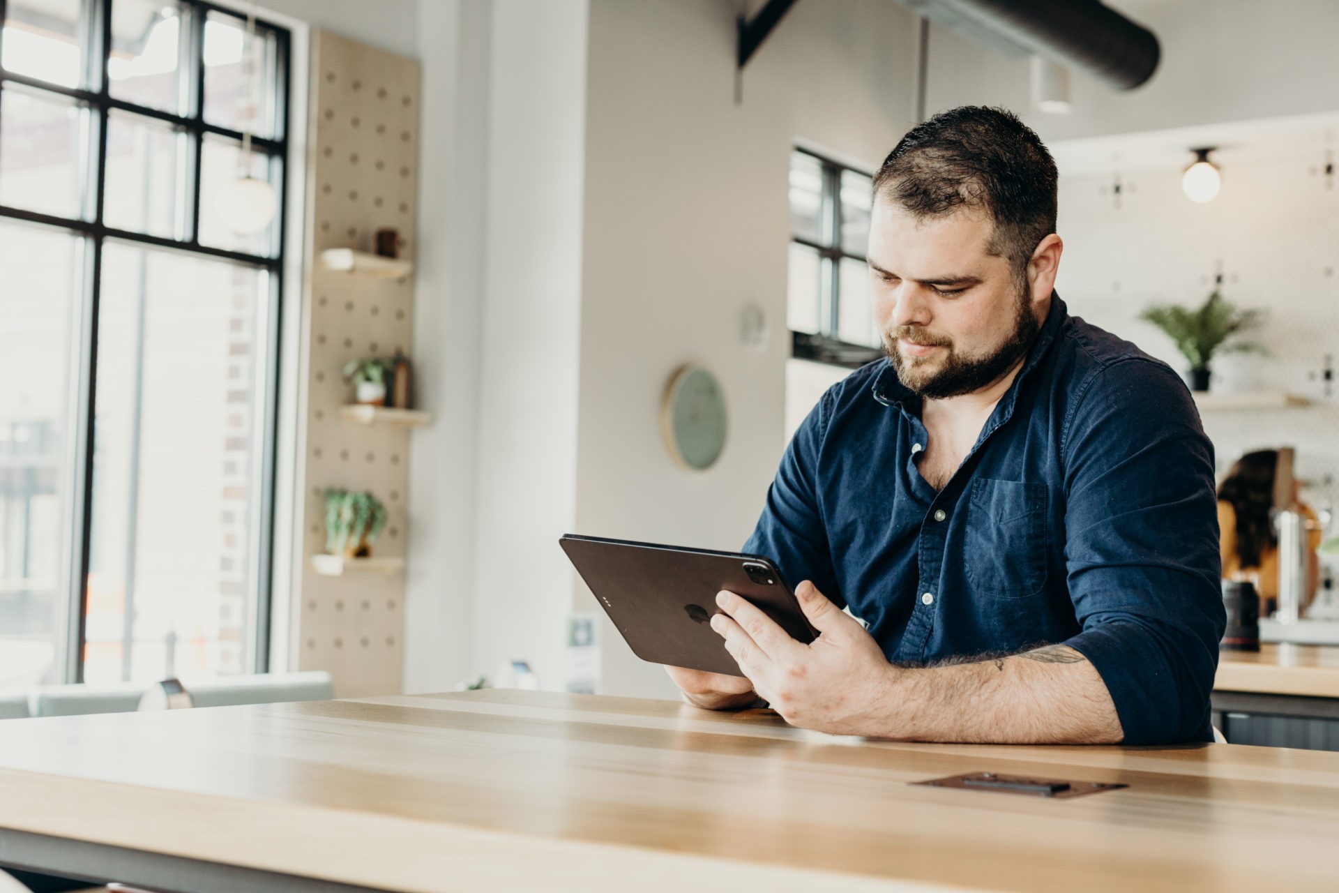 Man wearing navy blue button top looking at an IPad