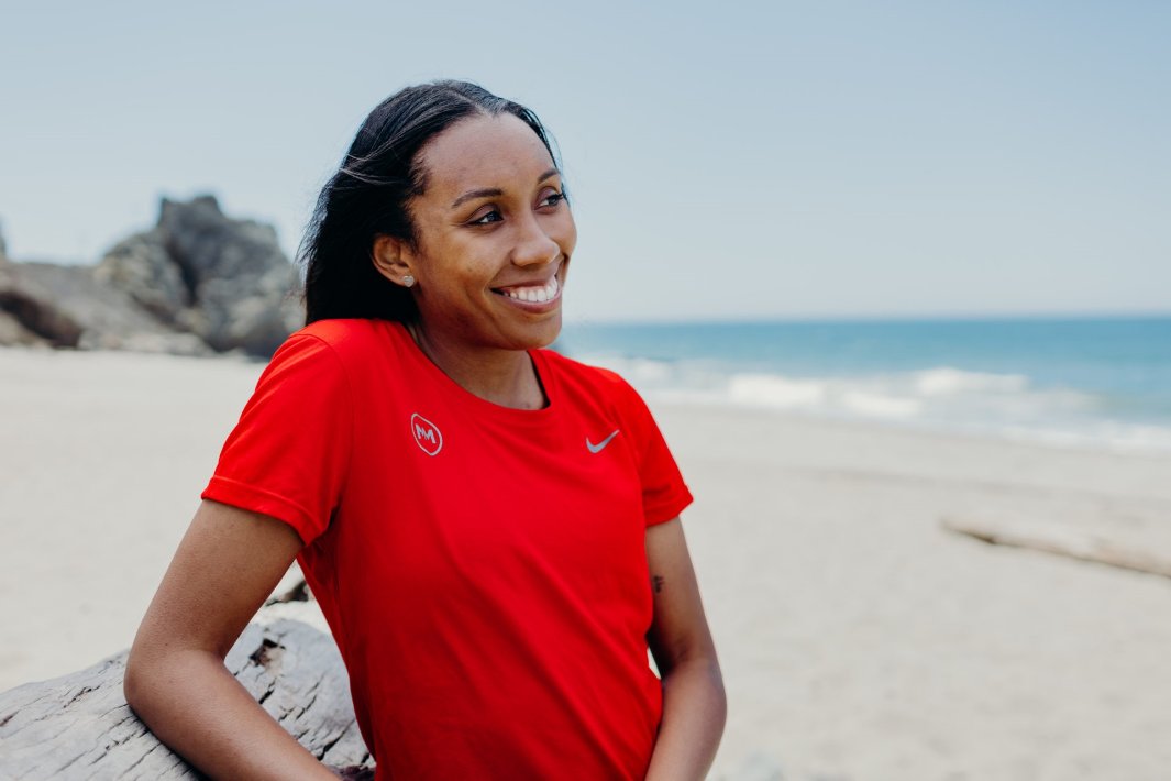 Woman wearing red MM t-shirt at the beach smiling