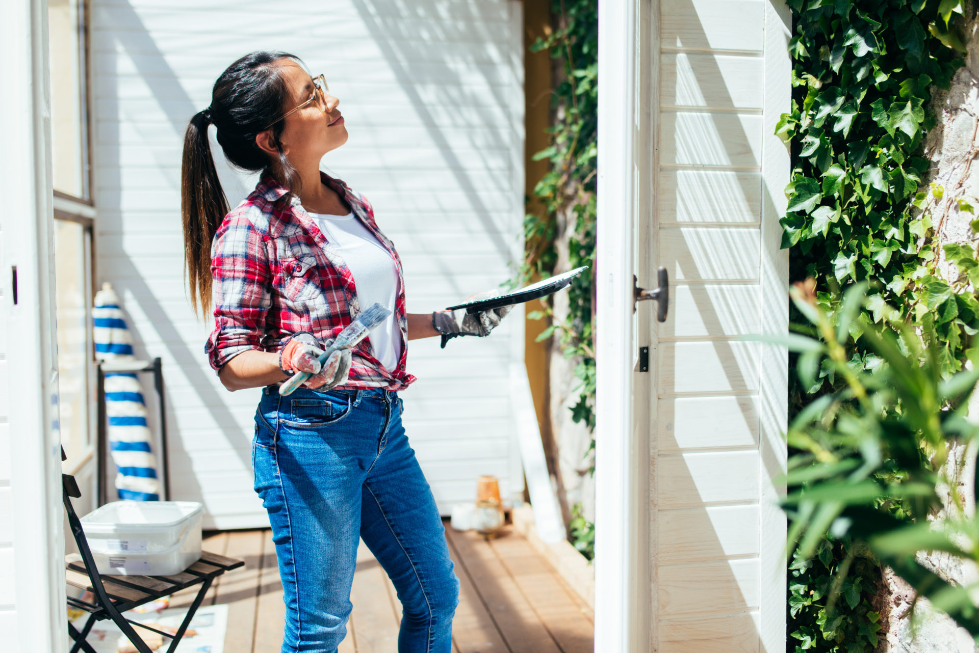 Proud woman painting garden house.