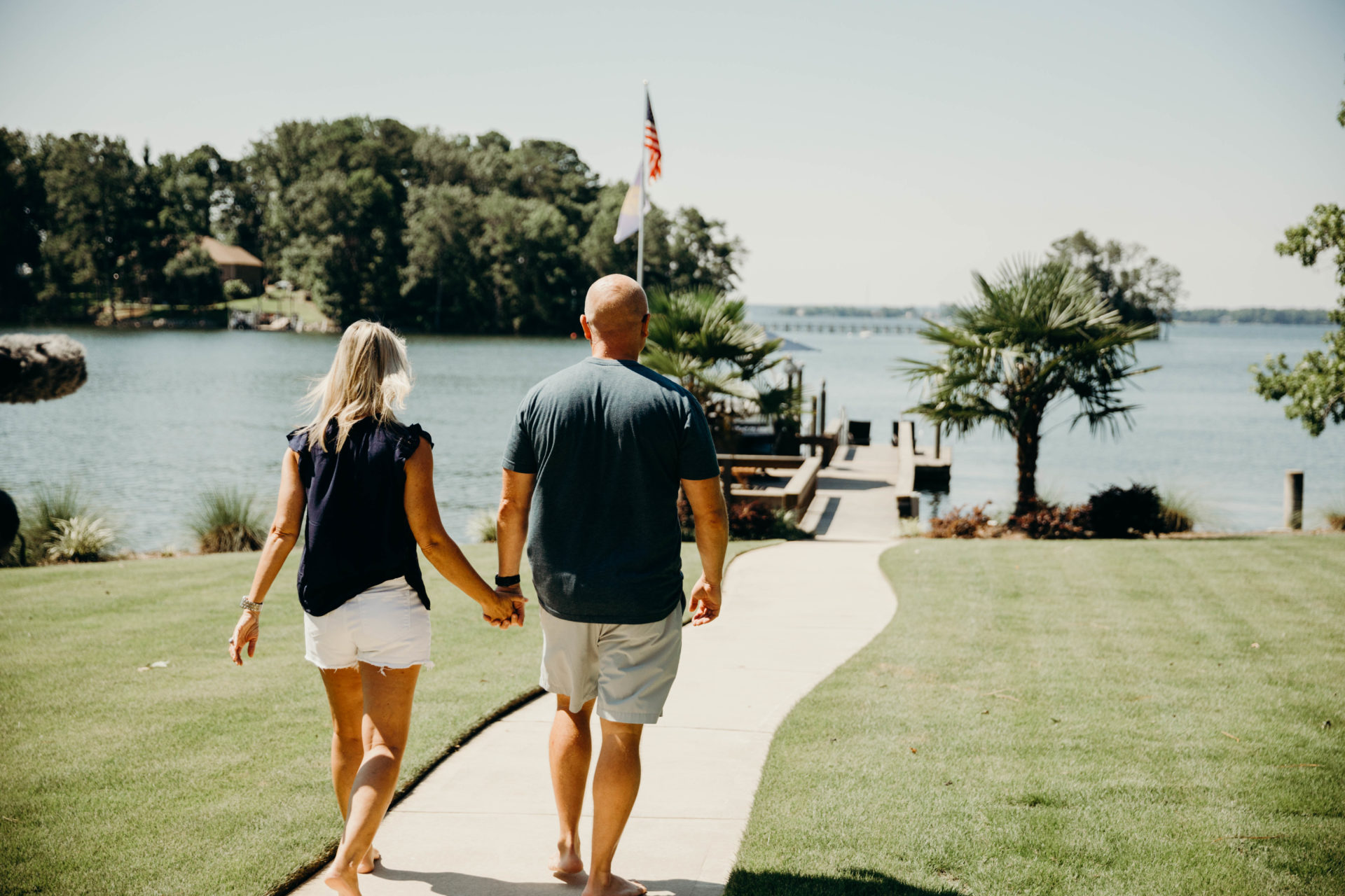 Couple holding hands walking down to the lake