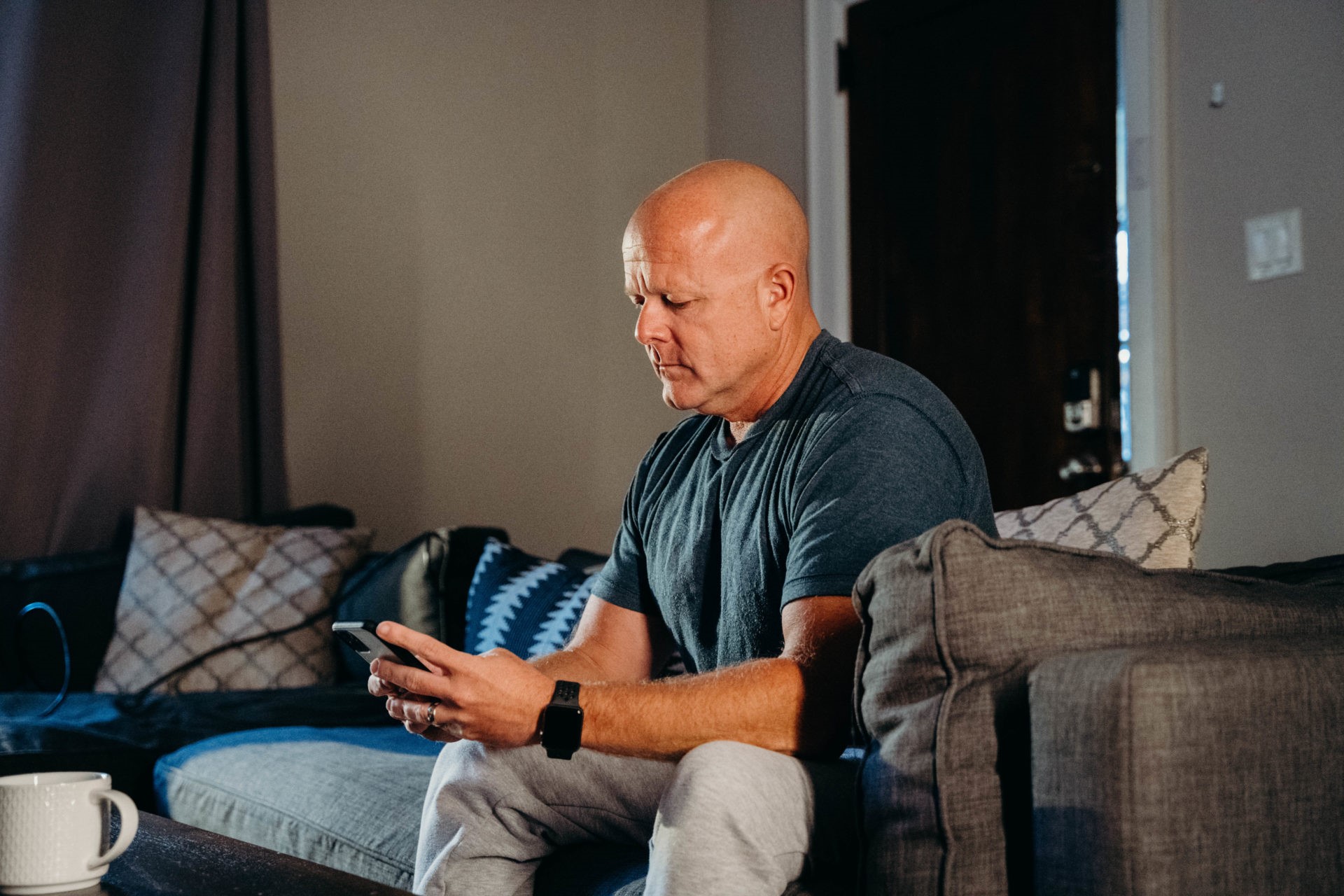 Older man sitting on his couch looking at his phone