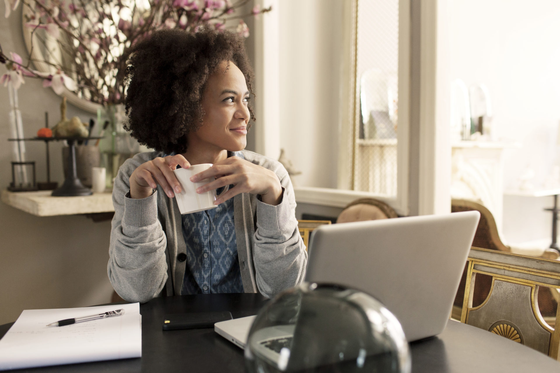 Smiling woman with mug looking away sitting at table