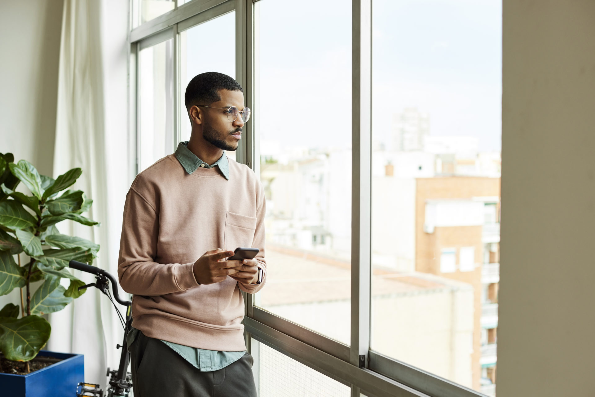 Contemplating Man With Phone Looking Through Window