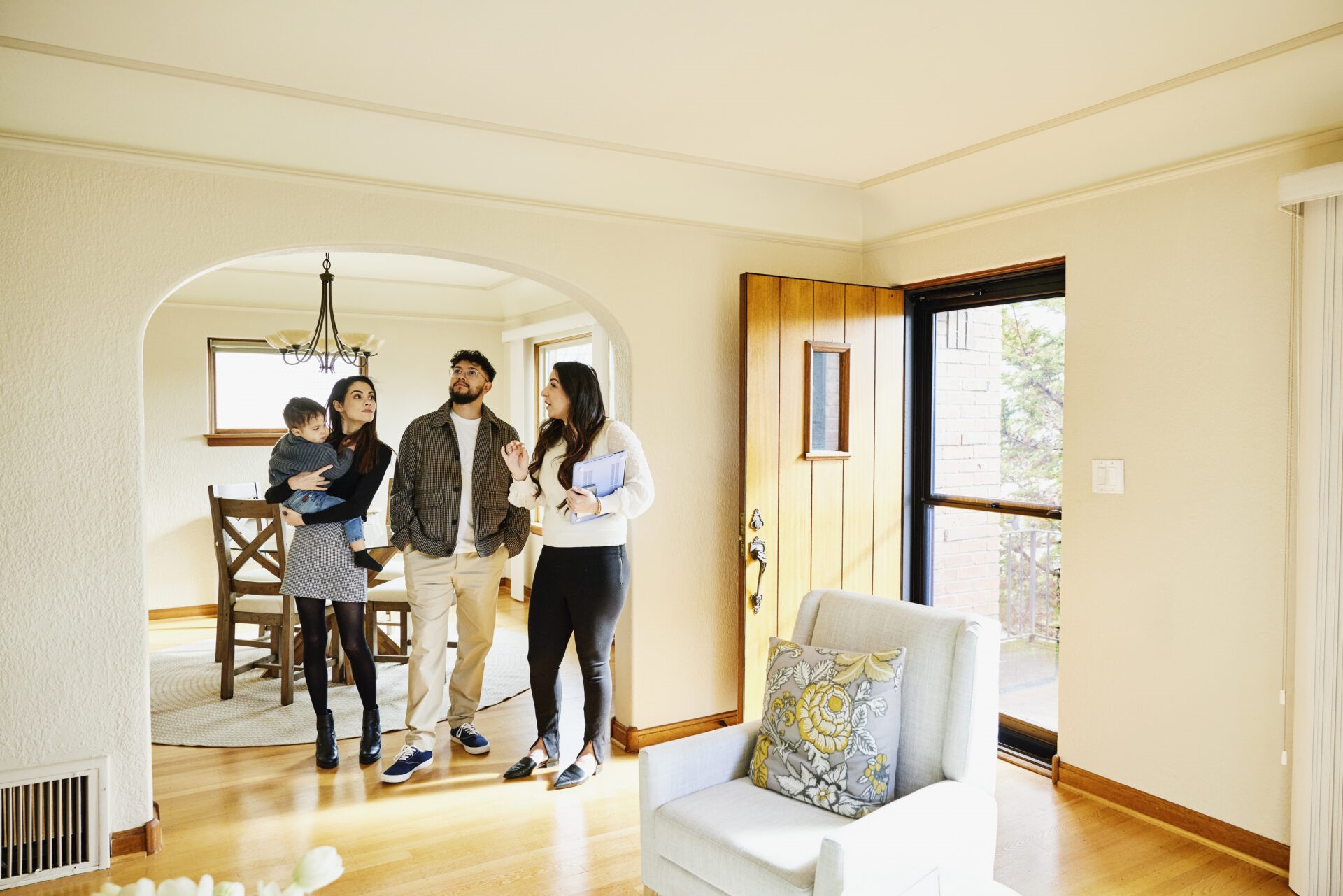 Wide shot of family looking at home for sale with real estate agent