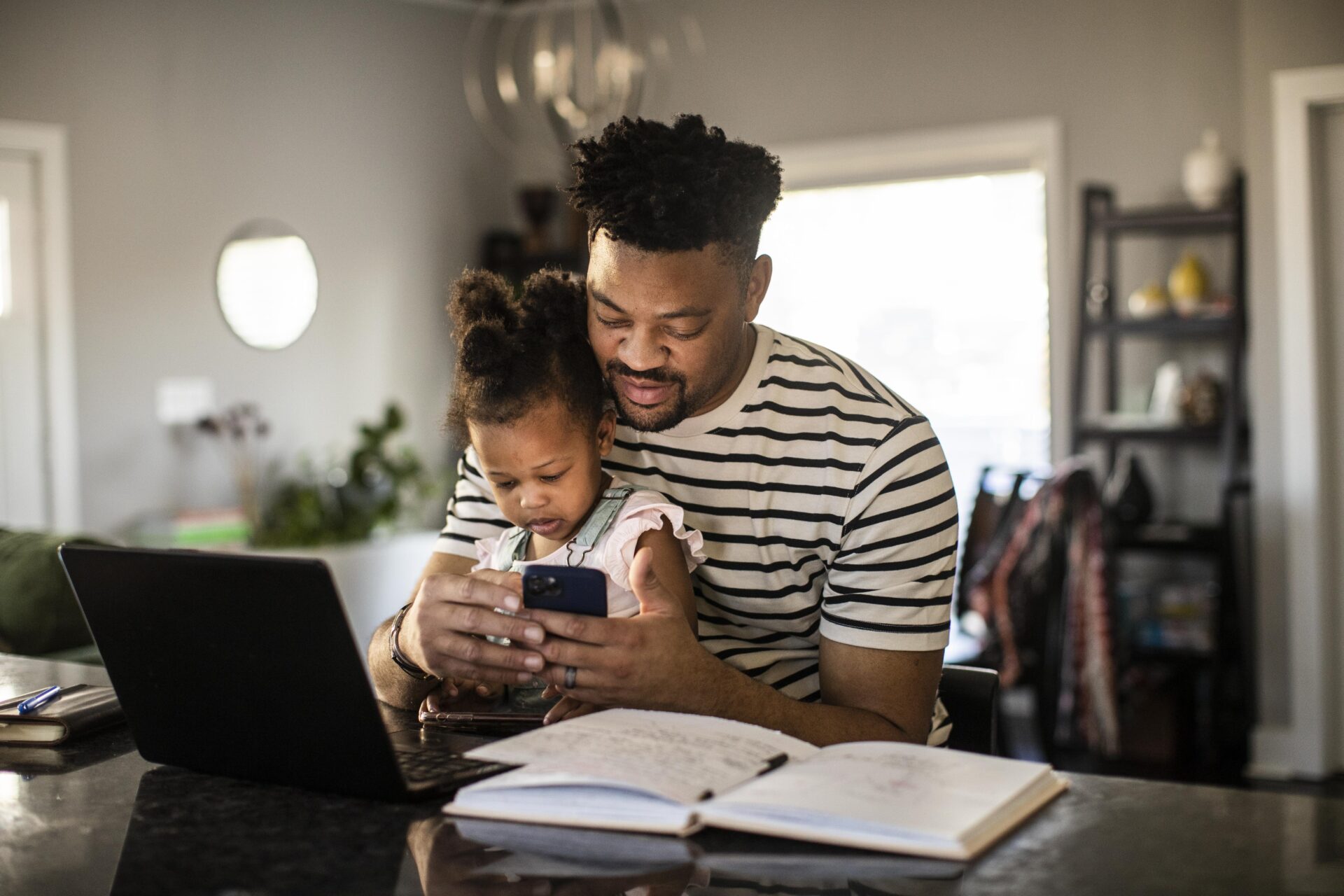 Father working from home while holding toddler