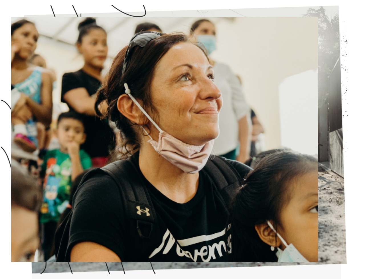 Stylized image of smiling woman wearing mask below her chin surrounded by people