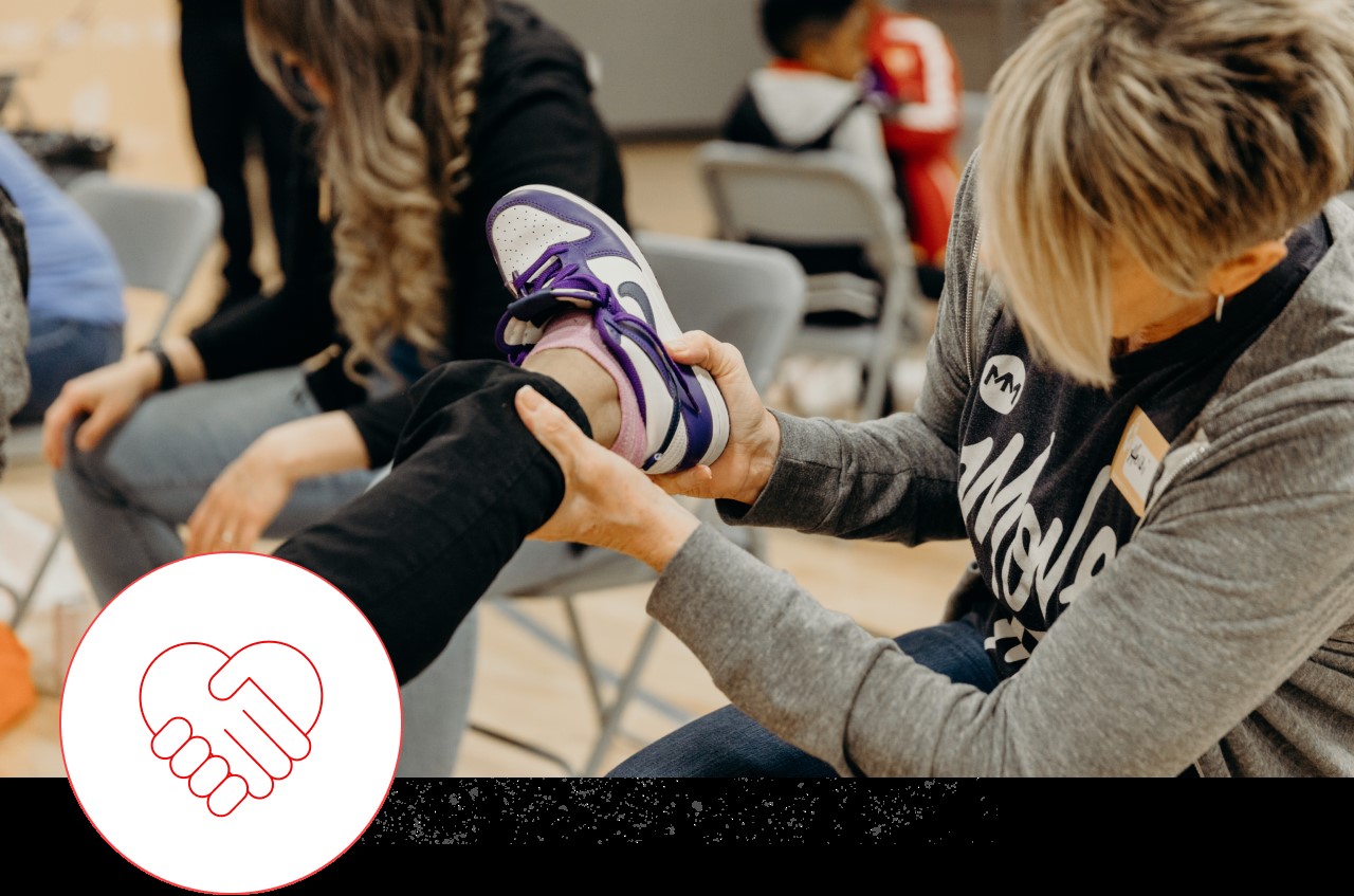 Movement volunteer helping a kid put on their shoes