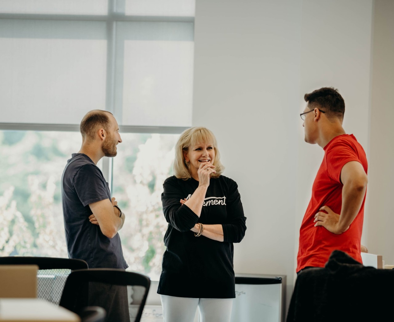 Three people standing and talking with one another in a relaxed position