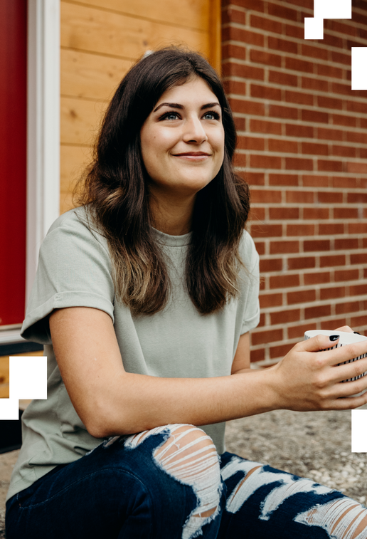Young woman drinking coffee outside her house