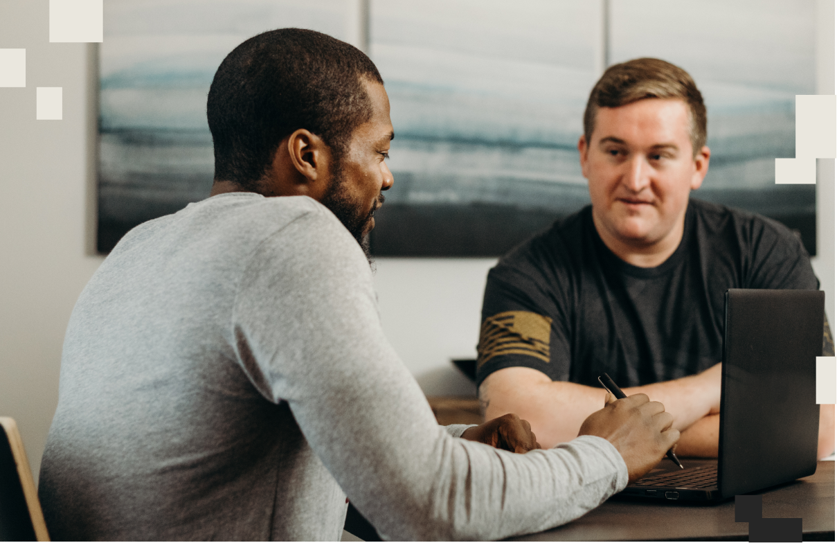 Two man sitting down with a laptop having a conversation