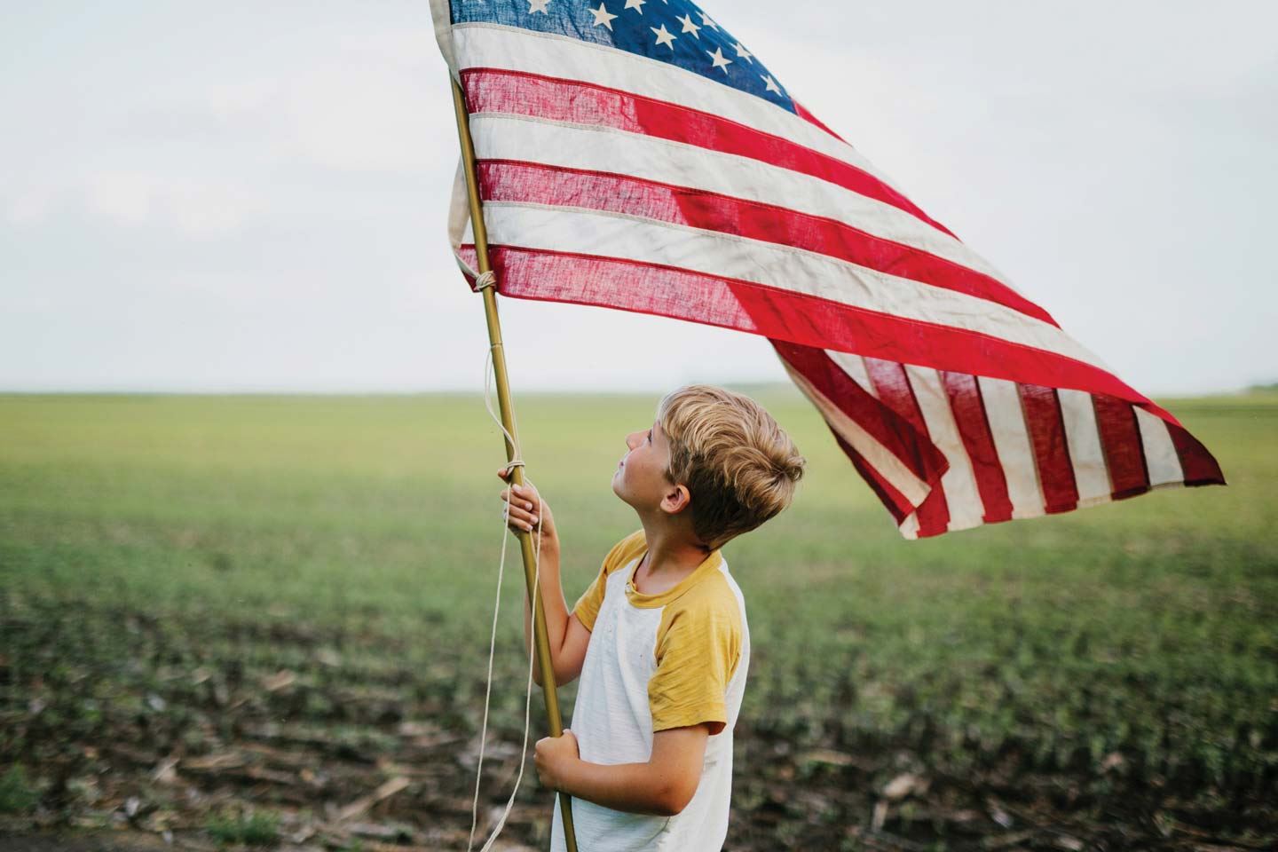 Young boy holding an American flag in a field